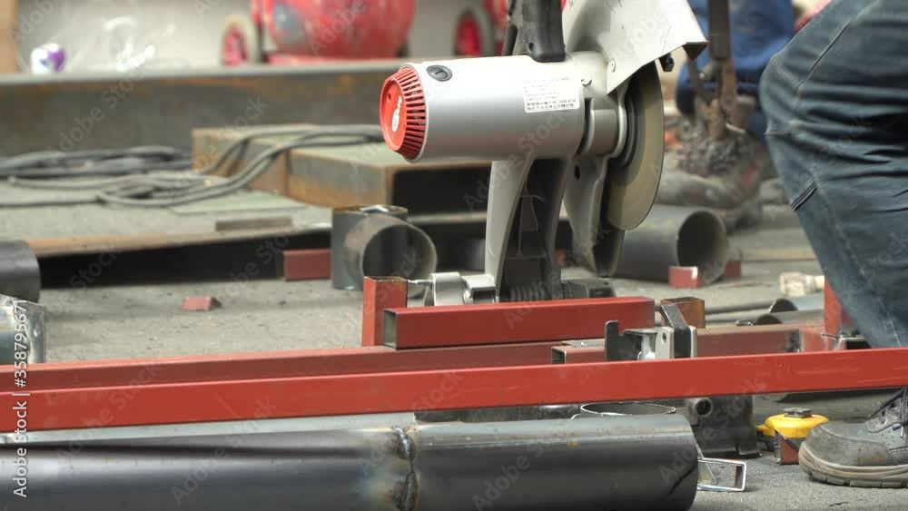 Male Worker Cutting A Metal Tubular With Cut-off Machine - close up Male Worker Cutting A Metal Tubular With Cut-off Machine - close up