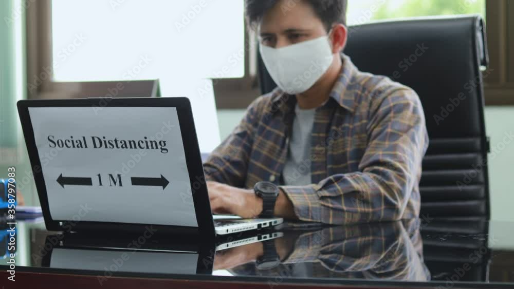 Young Asian man with mask and using computer working in office Young Asian man with mask and using computer working in office
