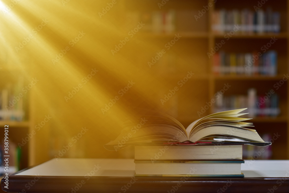 Open Book on wood table and blurred bookshelf in the library, education background, back to school concept. Open Book on wood table and blurred bookshelf in the library, education background, back to school concept.