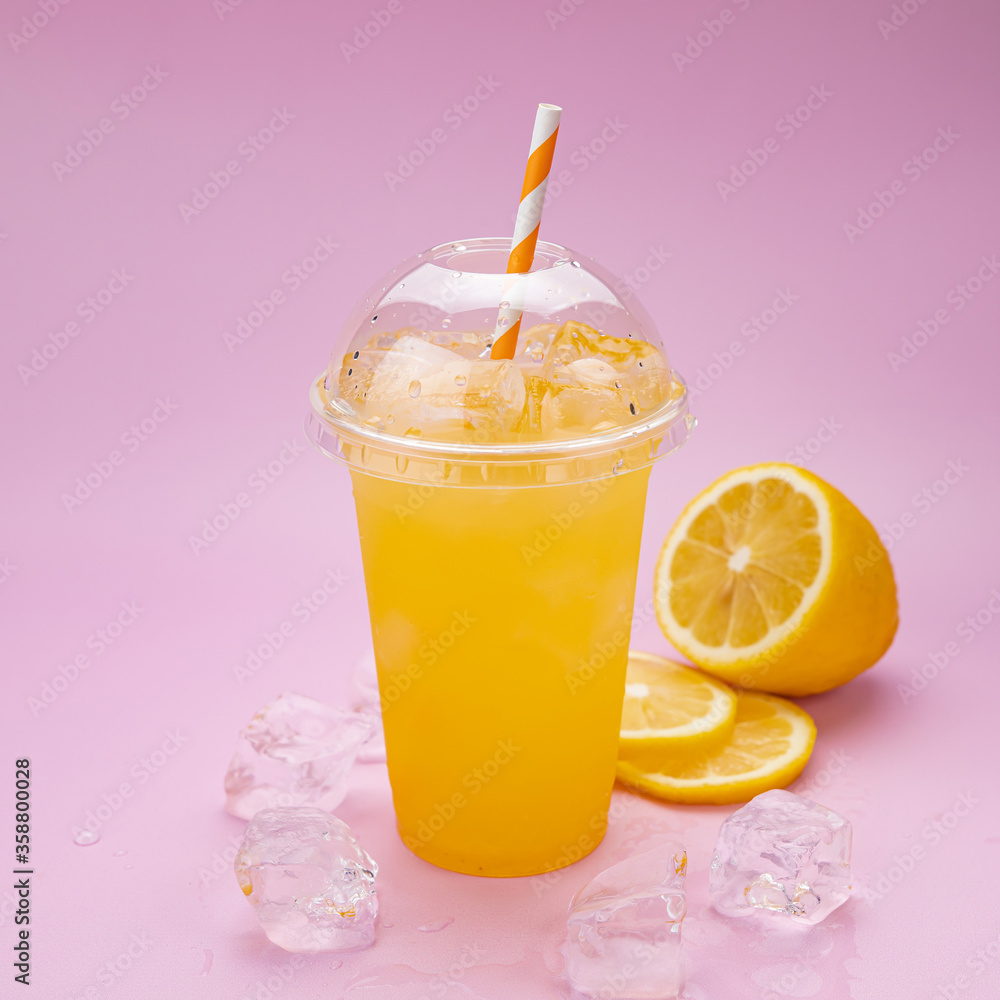 Summer Drink Fresh Lemonade with orange in the plastic cup on a pink