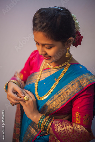 Portrait of Indian girl wearing traditional jewellery. Looking down nd blushing. Observing her ring in Maharashtrian Nauvari saree photo