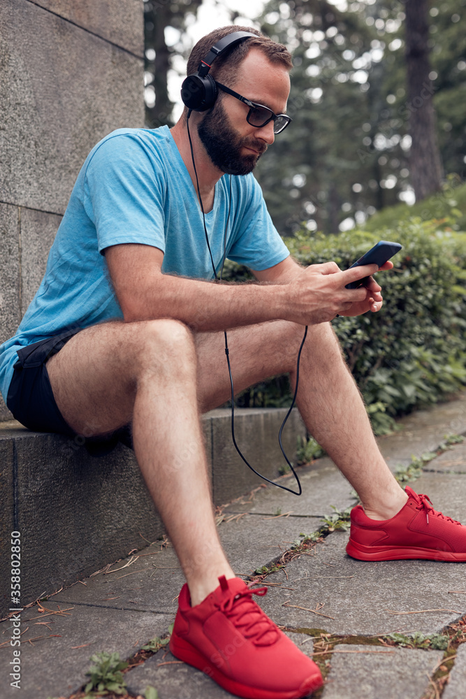Modern sporty adult man making pause in the park after exercising / running and jogging. Modern sporty adult man making pause in the park after exercising / running and jogging.