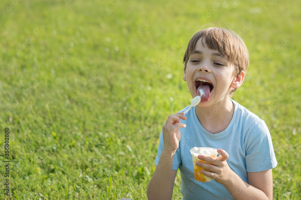 Caucasian boy eats ice cream on hot summer day sitting on grass Caucasian boy eats ice cream on hot summer day sitting on grass