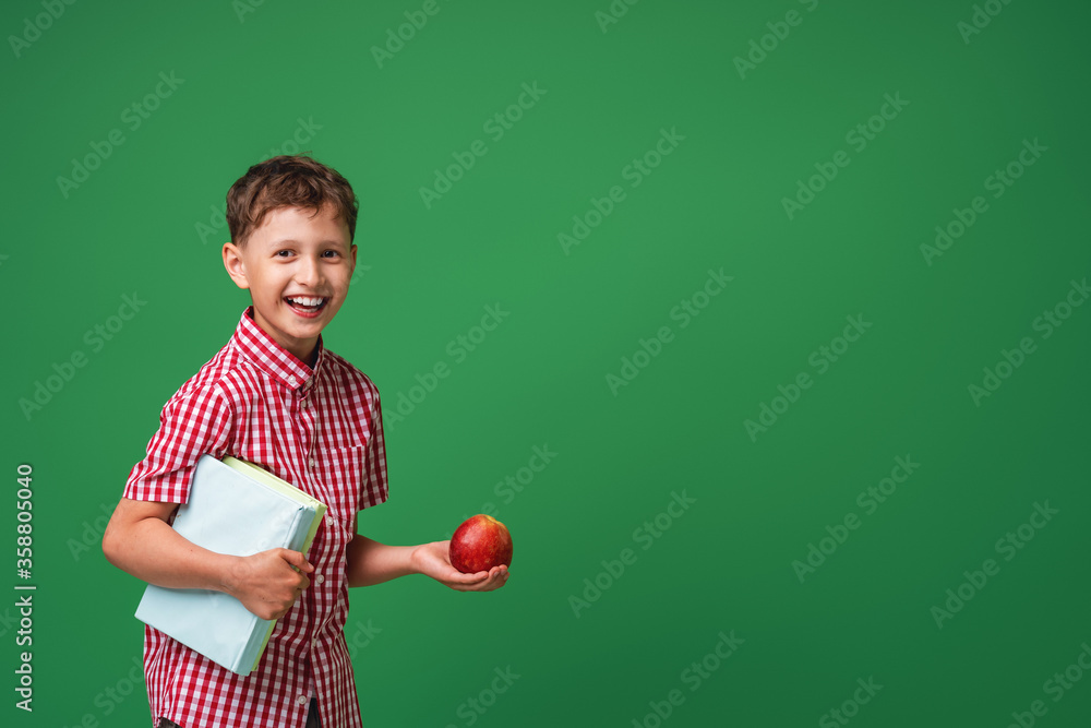cheerful, mischievous boy holds books and an Apple in his hands cheerful, mischievous boy holds books and an Apple in his hands