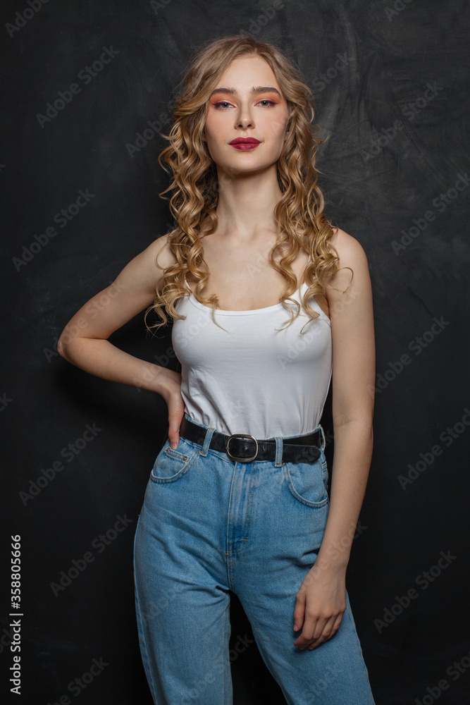 Posing blonde woman in blue denim on black background