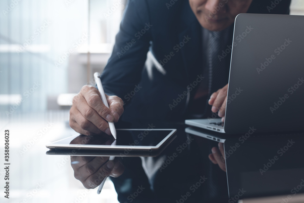 Asian businessman manager working on digital tablet and laptop computer in modern office Asian businessman manager working on digital tablet and laptop computer in modern office