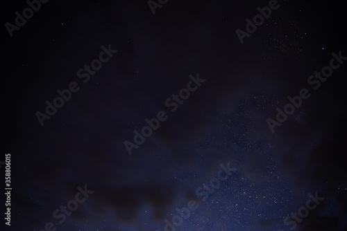 Stars in the night sky through the clouds on a summer night