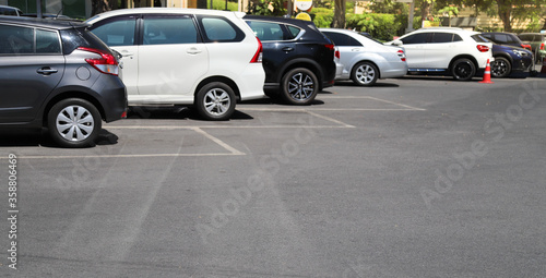 Closeup of rear, back side of black car with  other cars parking in outdoor parking in bright sunny day.  © Amphon