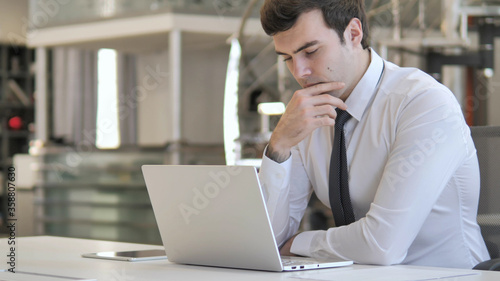 Fotografie Pensive Young Businessman Thinking  and Working on Laptop