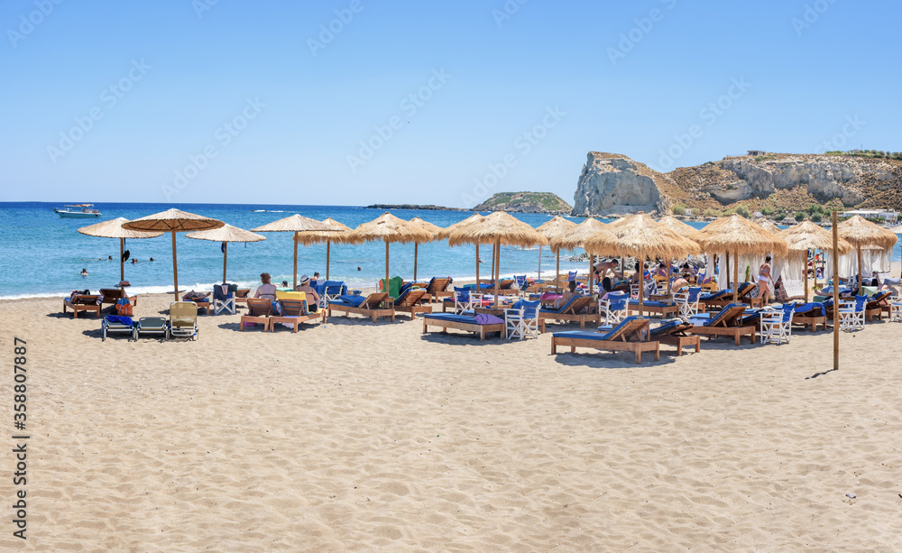 Holiday-makers, sun beds and umbrellas on Stegna beach (RHODES, GREECE)