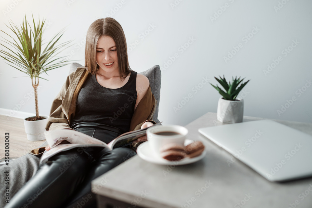 Young Adult Girl Reads a Magazine Sitting on Sofa Young Adult Girl Reads a Magazine Sitting on Sofa
