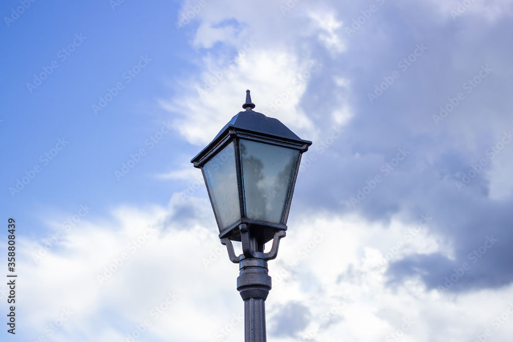 old street light against the sky, the sky is reflected by the glass of a lantern