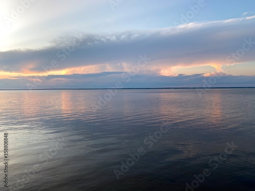 Pastel cloudy sunset over bay water