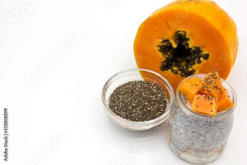 Jar of vegan pudding with chia, almond milk, papaya next to the ingredients on white background. Space for text. Healthy vegetarian food. Lactose free dessert