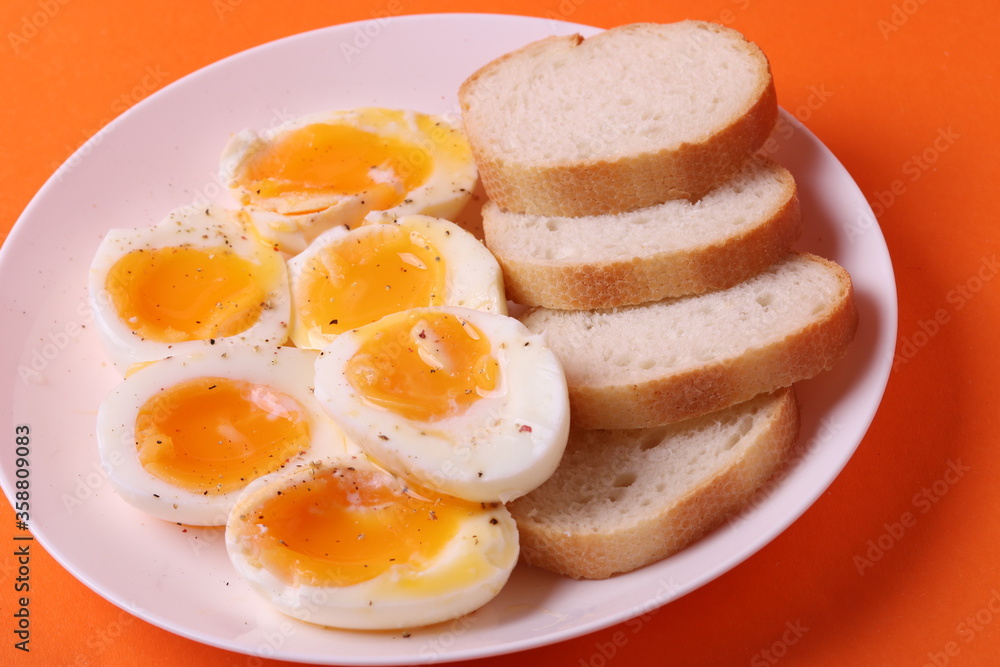soft-boiled sunny side up halves of chicken eggs on the white plate bright orange background. close up shot. minimalism concept soft-boiled sunny side up halves of chicken eggs on the white plate bright orange background. close up shot. minimalism concept