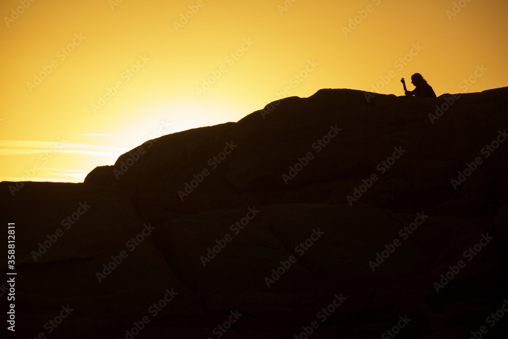 silhouette of woman standing on top of mountain in the sunset