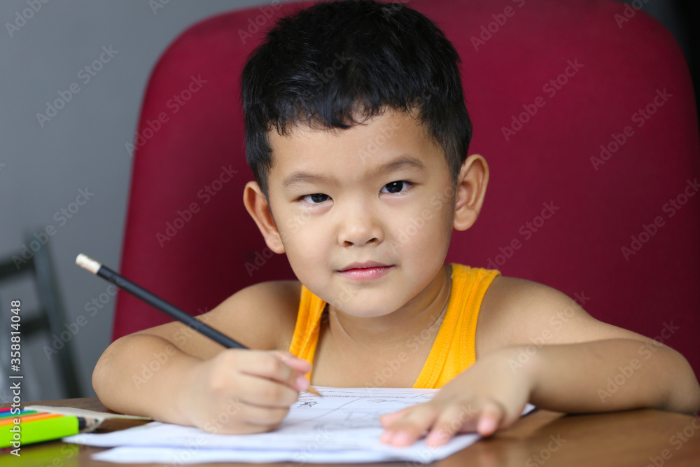 Asian boy is doing his homework,concept of studying on-live at home.