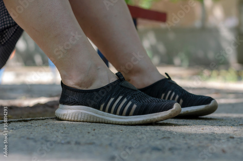 Legs in sneakers of a woman resting on a street bench. photo