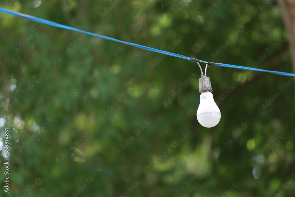 Obraz premium One white light bulb connected to an old blue electric wire