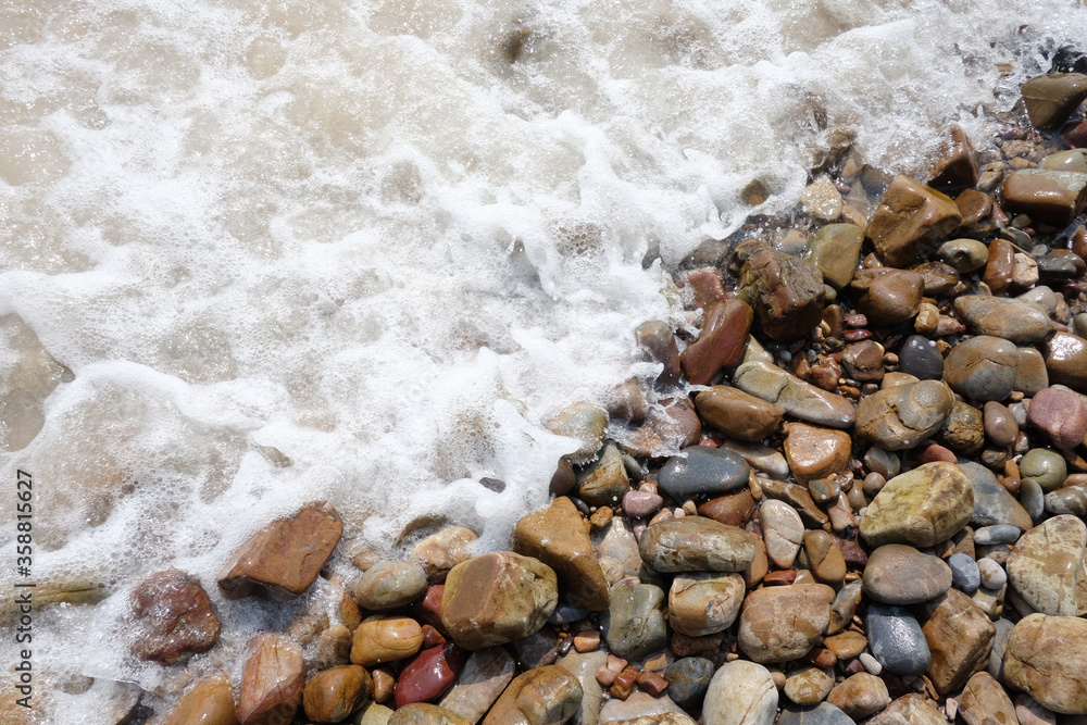 Waves lapped at the seashore scree or pebbled beach background.