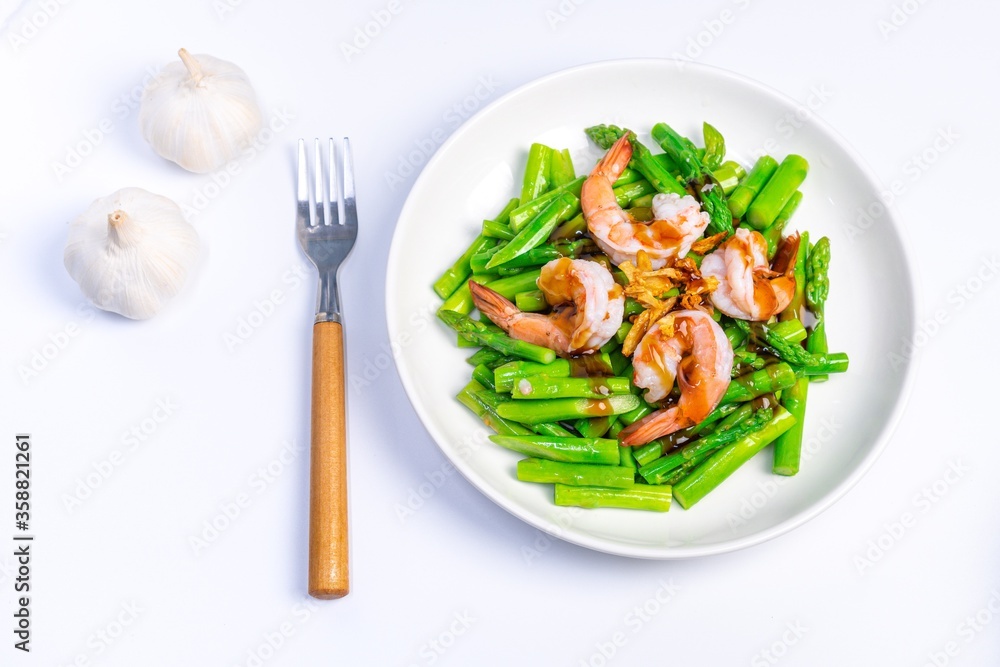 Stirred fried asparagus with shrimp served on white plate isolated on white background. famous thai food in thailand. popular food in Asia. Stirred fried asparagus with shrimp served on white plate isolated on white background. famous thai food in thailand. popular food in Asia.