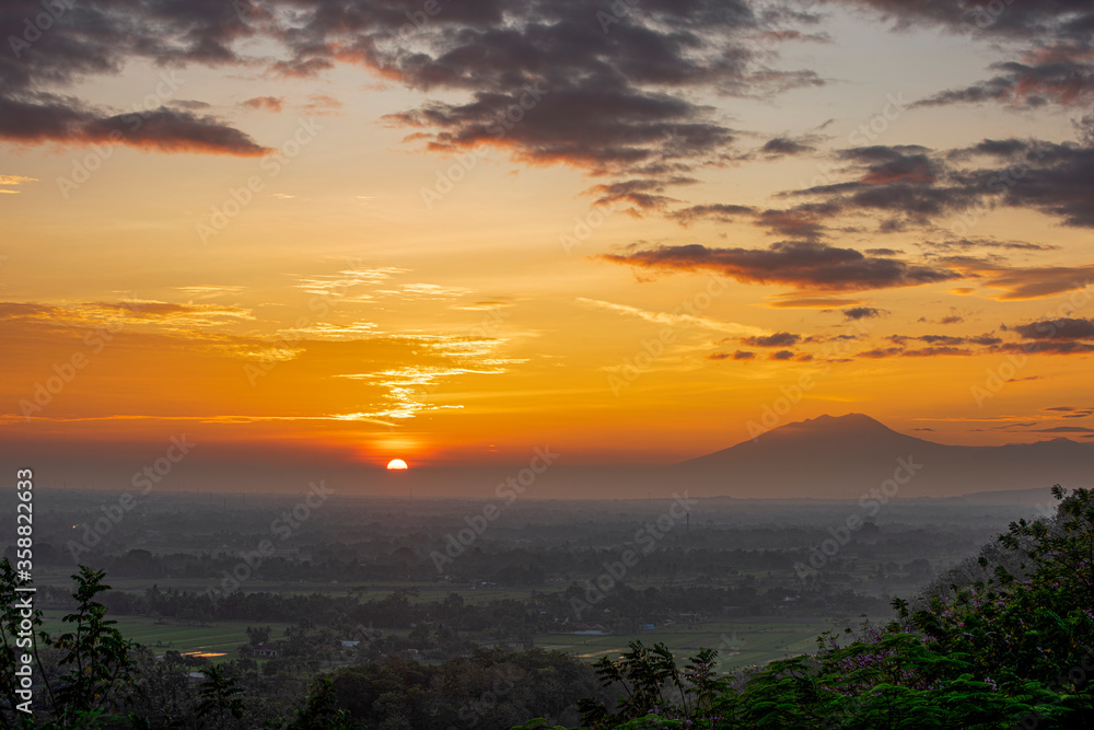 First light of beautiful sunrise in Java Island with Lawu Volcano and foggy land