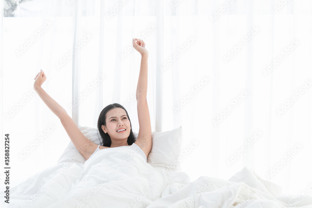 Beautiful woman lying and stretching on white bed in bedroom the morning Beautiful woman lying and stretching on white bed in bedroom the morning