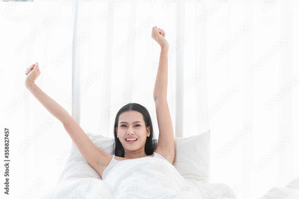 Asian people are beautiful, charming Stretching in the morning on the bed in a white bedroom. Asian people are beautiful, charming Stretching in the morning on the bed in a white bedroom.