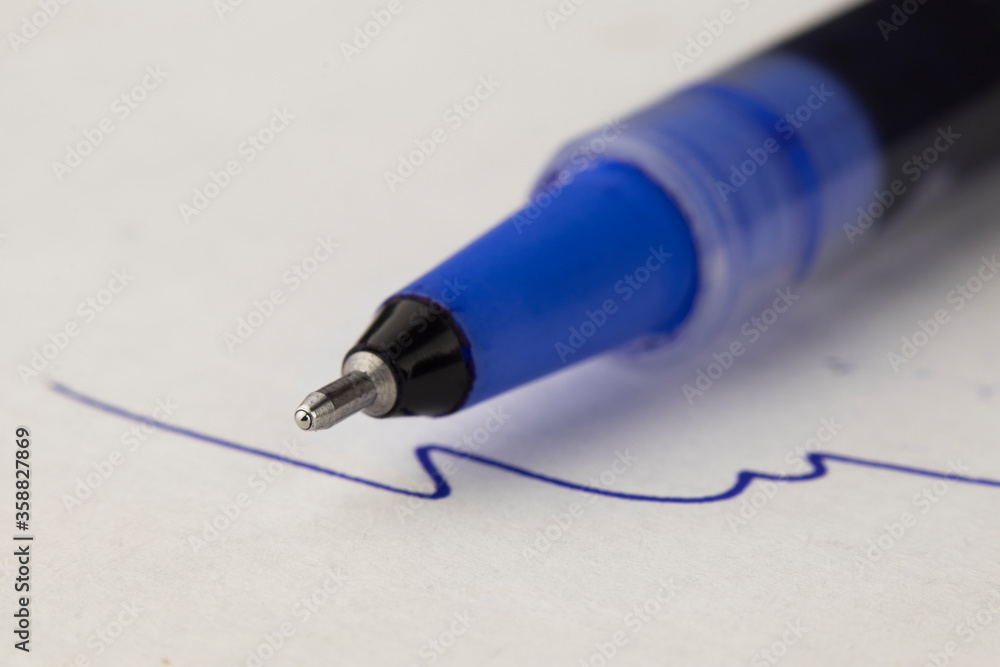 Fototapeta premium macro photo of the blue ballpoint pen on the white page paper