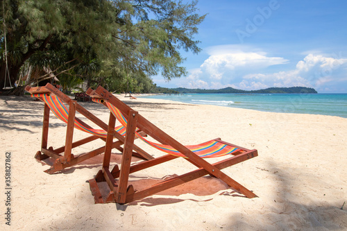 Beautiful tropical paradise white beach with sunbeds under coconut palm trees on island. Beautiful beach and beautiful palm tree travel summer holiday concept.