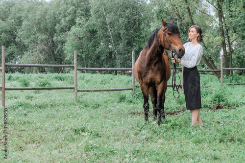 Young woman with horse in nature. Brunette girl and horse.