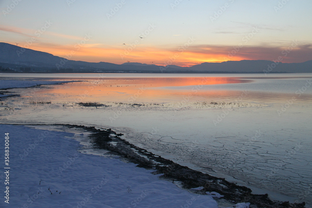 Sunset on the snowy lake beach