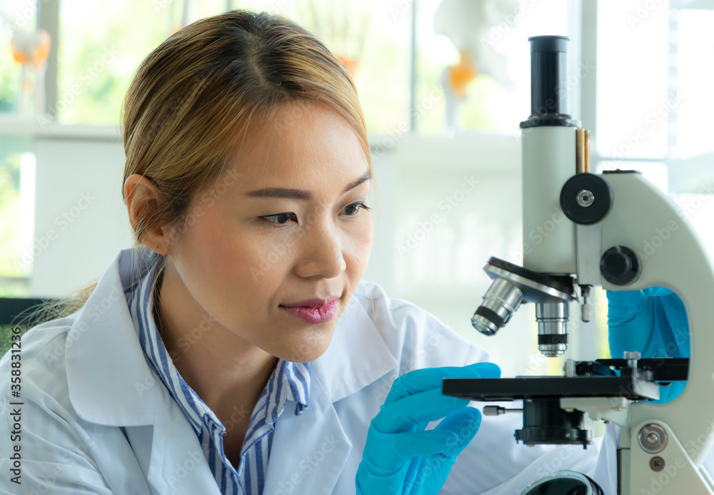Young scientist looking through a microscope in a laboratory. Health care researchers working in life science laboratory Young scientist looking through a microscope in a laboratory. Health care researchers working in life science laboratory