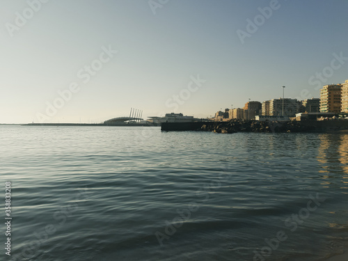 Genova, Italy - 06/18/2020: Beautiful photography of the sunset over the sea and clouds reflection on the water. Panoramic view to the ligurian coast in spring days. © yohananegusse
