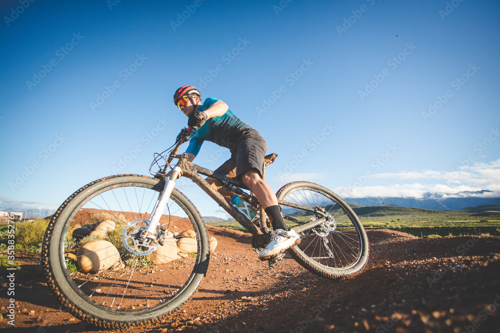 Wide angle view of a mountain biker speeding downhill on a mountain bike track.