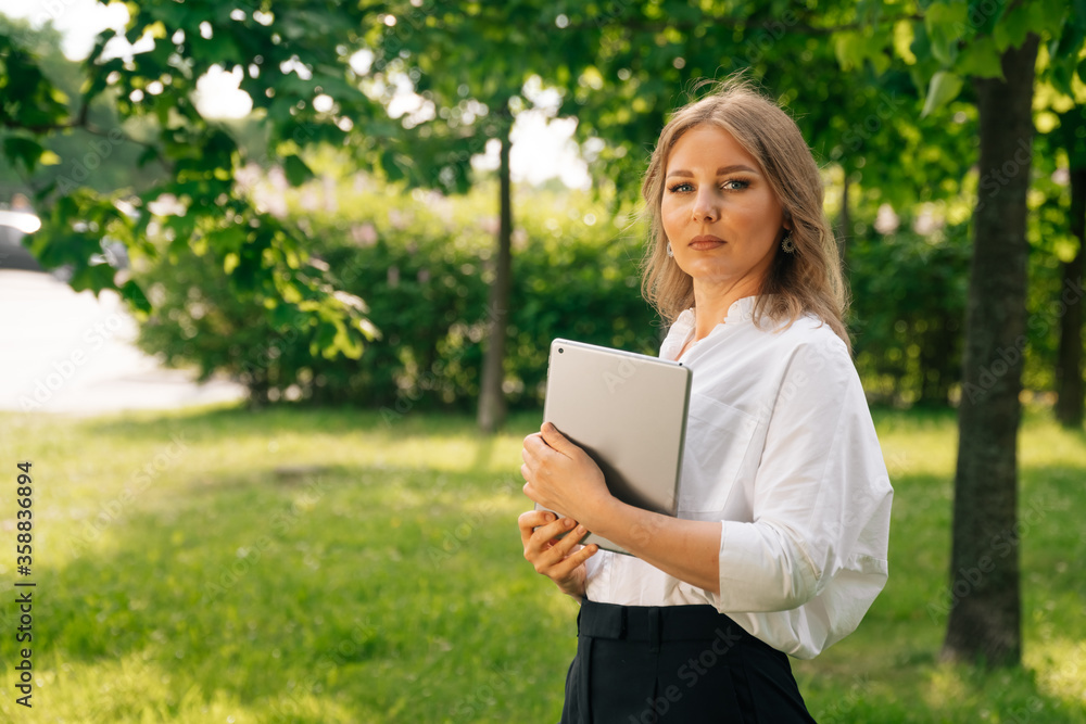 Portrait of confident business girl looking at the camera. Businesswoman holds digital tablet in hand Portrait of confident business girl looking at the camera. Businesswoman holds digital tablet in hand