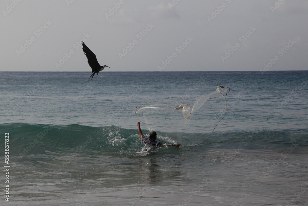 
fisherman with fishing net in the sea, fernando de noronha island, brazil