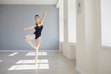 Ballerina. Young graceful ballet dancer is rehearsing a performance in a white studio with windows.