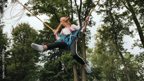 Photography Teenage girl jumping on the trampoline bungee.