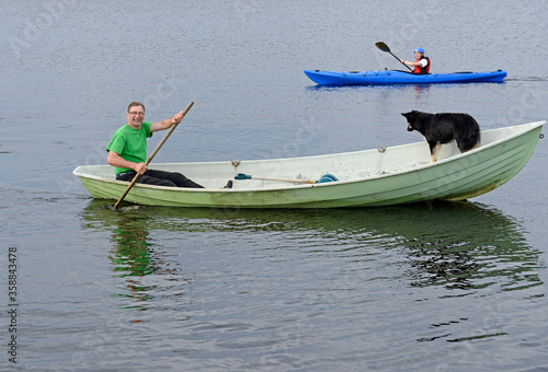 Family on lake. Man with dog on boat and young man on kayak. Finnish Lapland photo