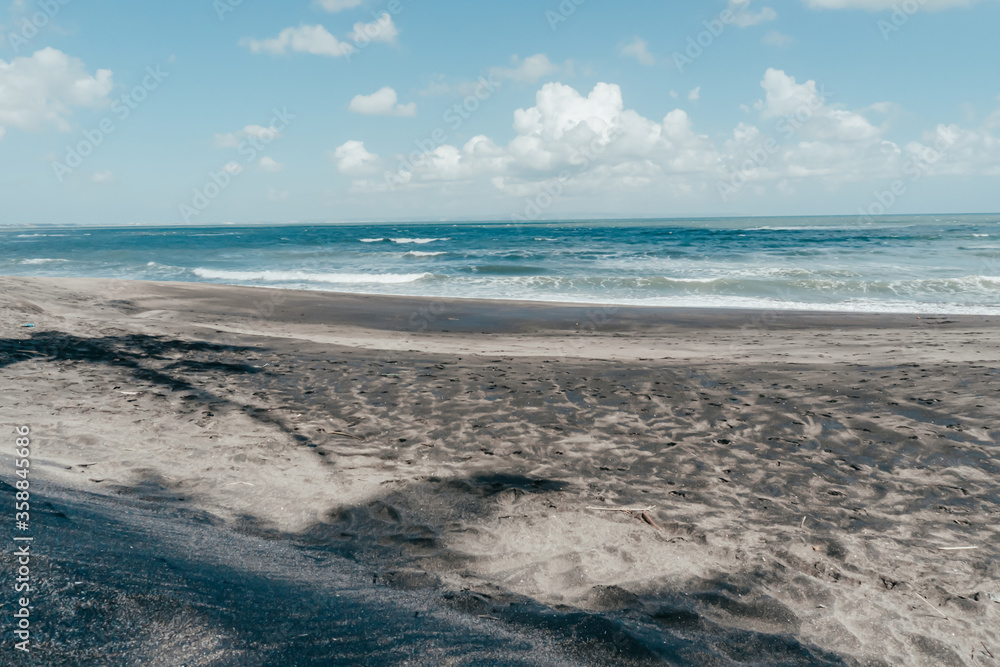 large waves crashing in sand beach rocks on bali island