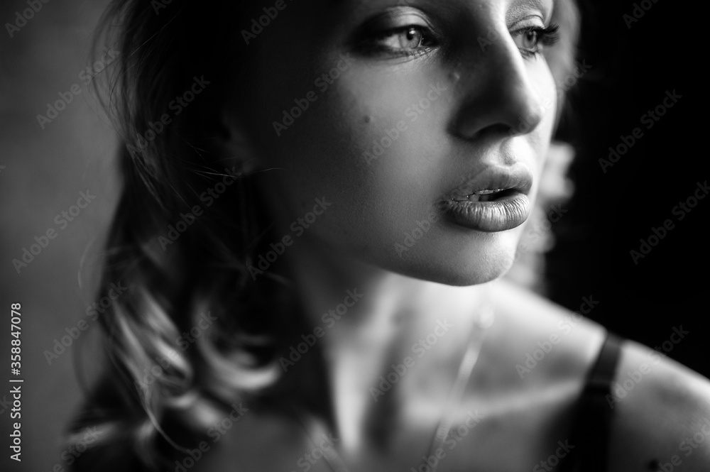 Fototapeta premium Close up monochrome portrait of curly blond charming woman with cool lips.