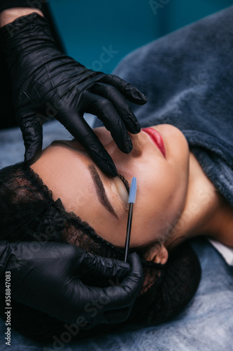 lamination of eyelashes in a beauty salon  master in black gloves