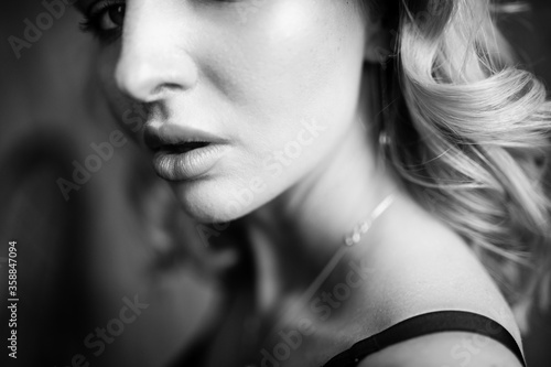 Close up monochrome portrait of curly blond charming woman with cool lips.
