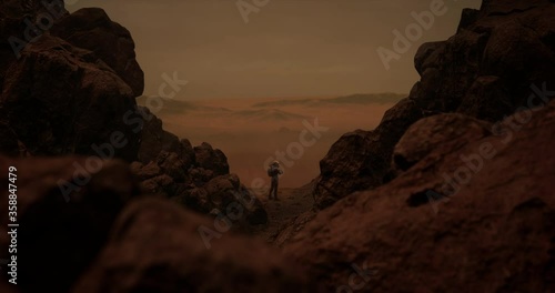 DOLLY IN Back view of lonely astronaut walking on a surface of a red rocky planet. Mars colonization concept. Dust effect added