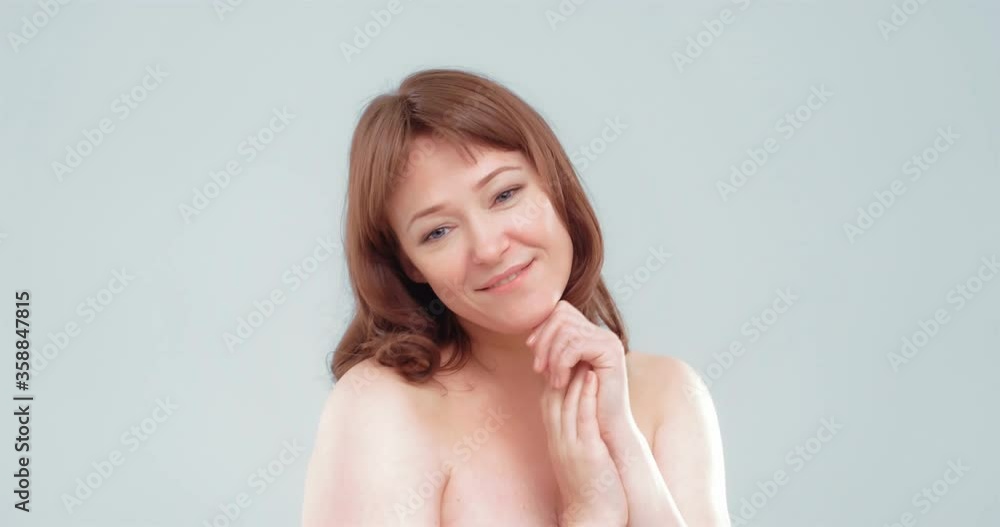 Beautiful cheerful mature woman applies skin care product, spa and wellness concept. Woman applying anti-age cream on her skin isolated on white background. Prores 422. Beautiful cheerful mature woman applies skin care product, spa and wellness concept. Woman applying anti-age cream on her skin isolated on white background. Prores 422.