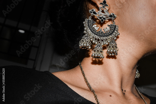 Close up of Indian girl wearing traditional earrings with chain in neck.
