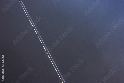 Dark brown leather with contrasting diagonal stitching. Textured background, space for your text