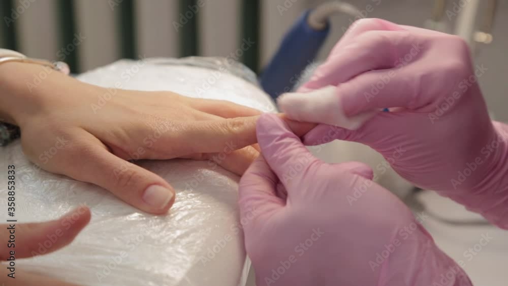 Manicurist wipes nails with a swab. Manicurist wipes nails with a swab.
