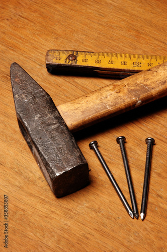 Hammer, metter and nails on a wooden table photo